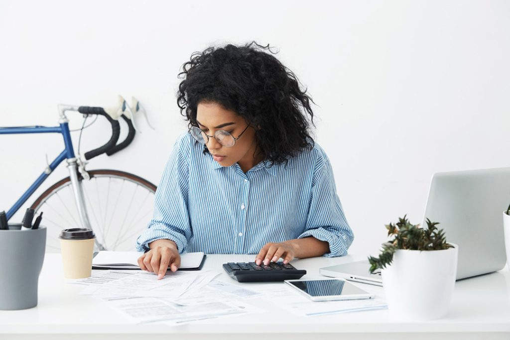 A young lady sitting at a table with a calculator, working on a debt management plan